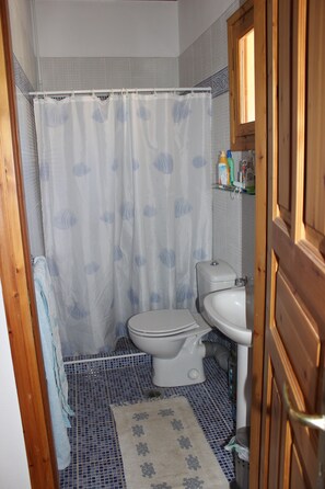 Un baño pequeño con inodoro, lavamanos y cortina de ducha.