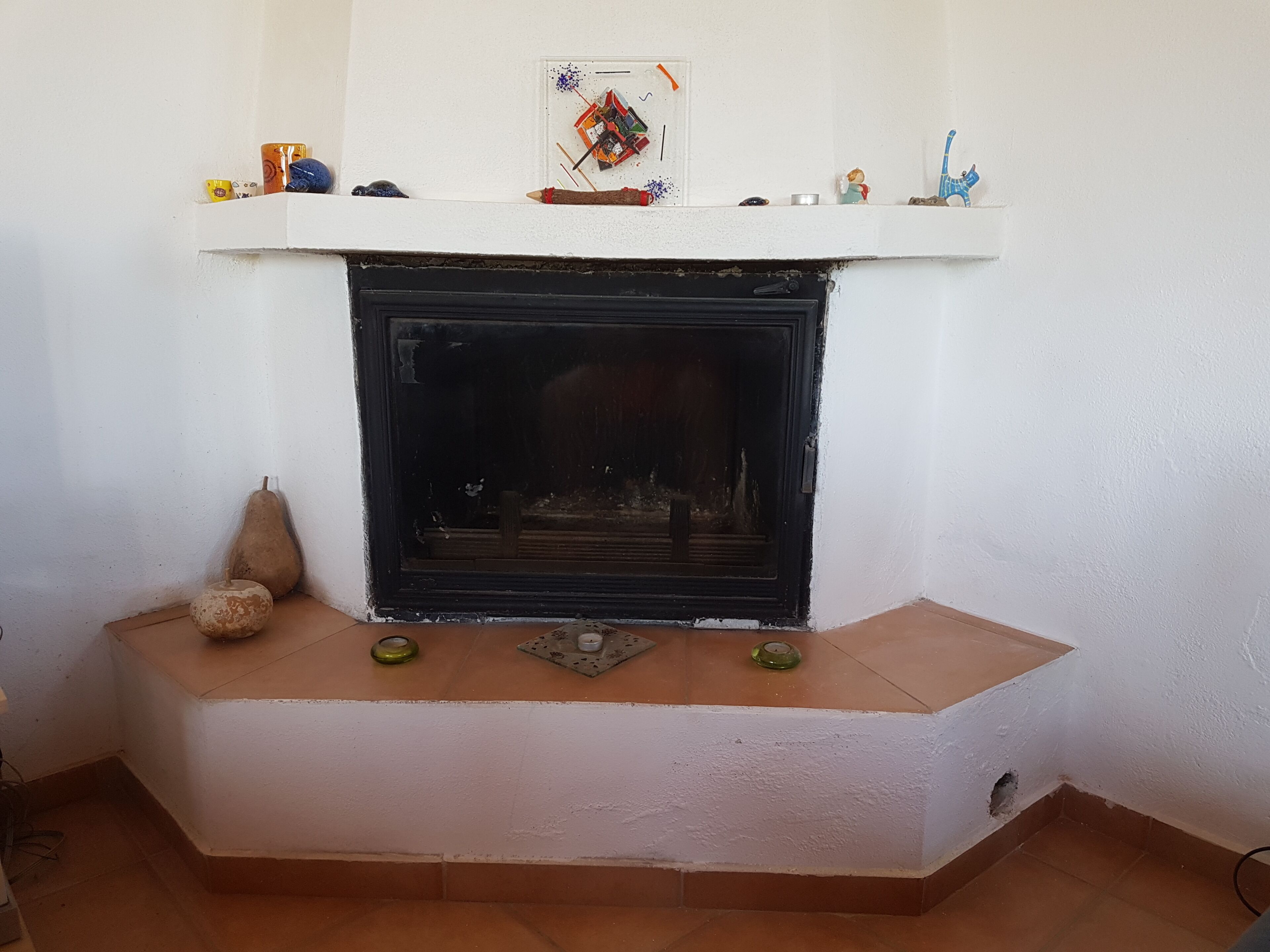 A fireplace with a white mantel, a small shelf above it, and a few decorative items.