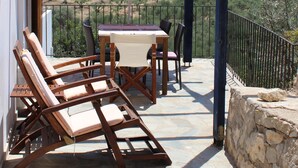 Un patio con muebles de madera, una mesa y un paraguas naranja.
