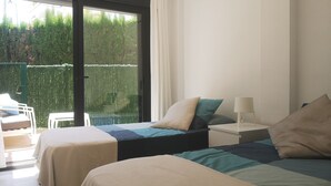A bedroom with two beds, a window, and a balcony.