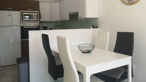 A modern kitchen with white cabinets, a microwave, and a dining table with chairs.