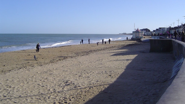 Una playa con gente caminando por la orilla.