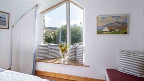 A room with a large window, a painting on the wall, and a bed with striped pillows. - Beachside holiday home in stunning location overlooking the wild Atlantic way. (Castlecove)