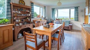 A cozy kitchen with wooden furniture, a dining table, and a view of the outdoors. - Beachside holiday home in stunning location overlooking the wild Atlantic way. (Castlecove)