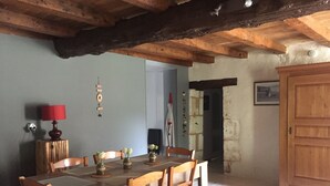 A dining area with a wooden table and chairs, a red lamp, and a wooden cabinet. - The little chabrou cottage for 5 people  (Marillac-Le-Franc)