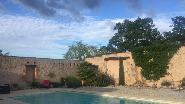A swimming pool with a stone wall and greenery in the background. - The little chabrou cottage for 5 people  (Marillac-Le-Franc)