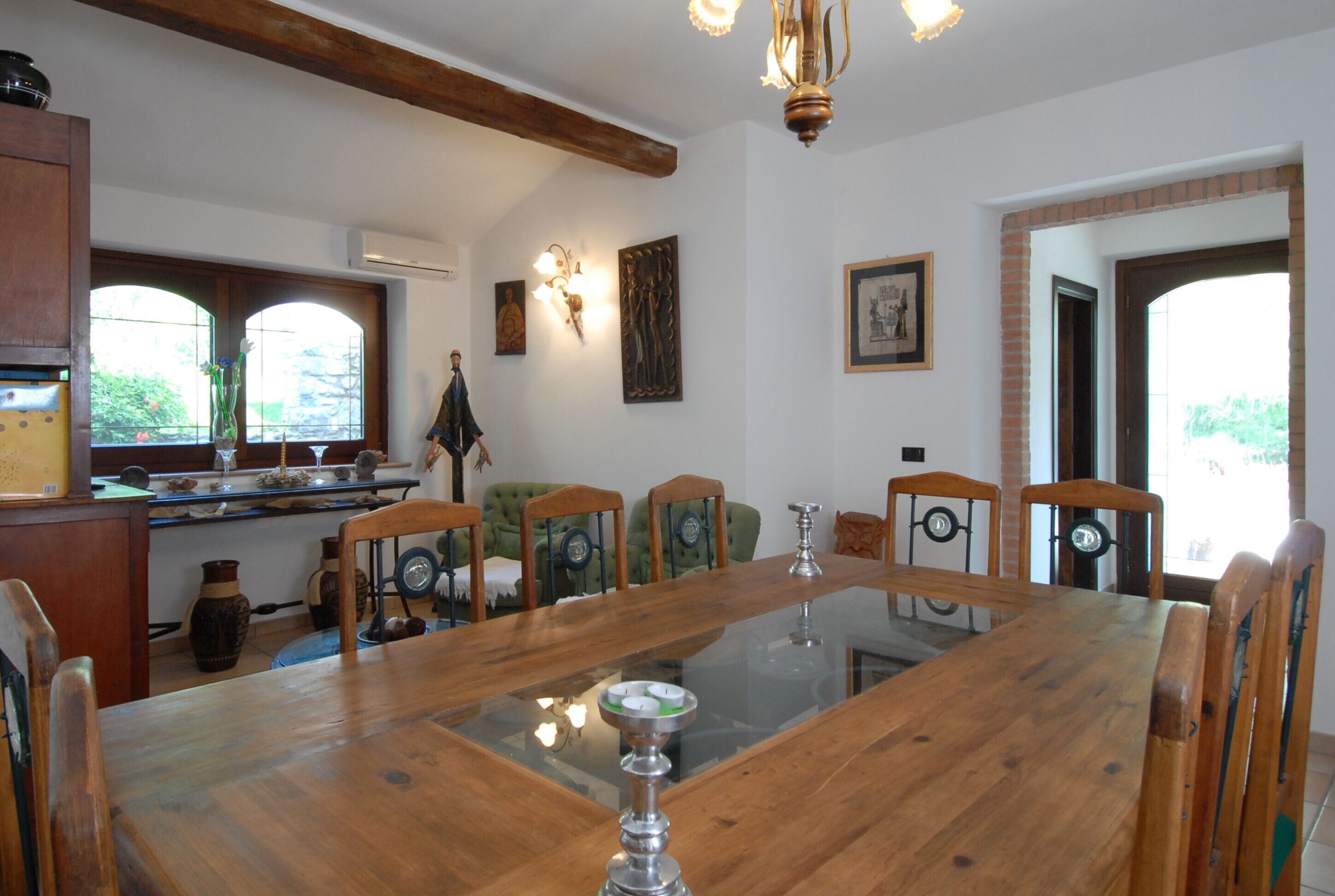 A dining area with a large wooden table, six chairs, and a chandelier.