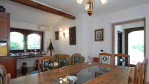 Un coin repas avec une grande table en bois, six chaises et un lustre.