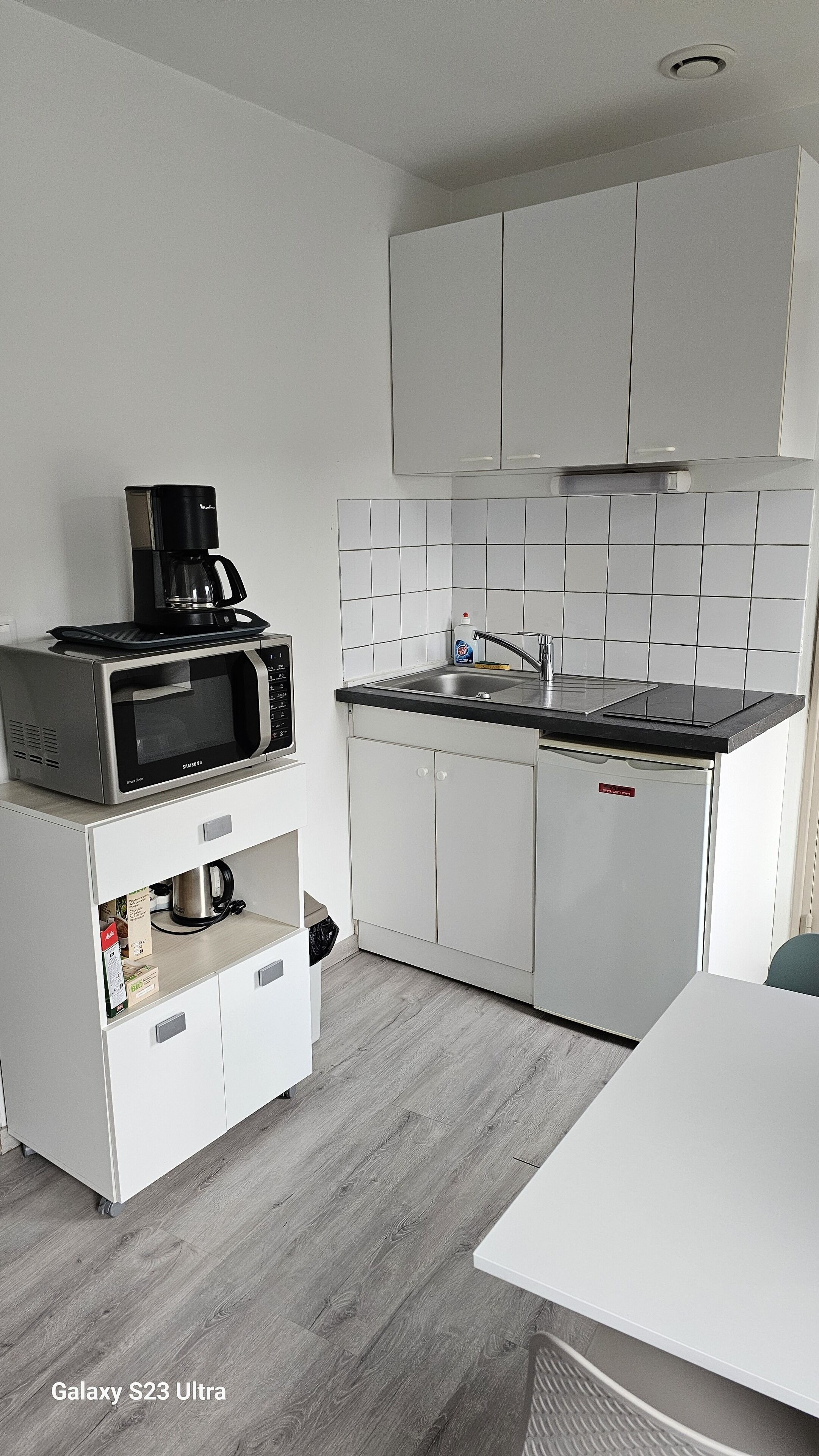 Une cuisine compacte équipée d’un four à micro-ondes, d’une machine à café, d’un évier et d’un lave-vaisselle.