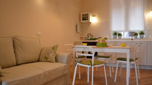 Un espacio habitable compacto con sofá, mesa de comedor, sillas, área de cocina con ventana y una kitchenette pequeña.