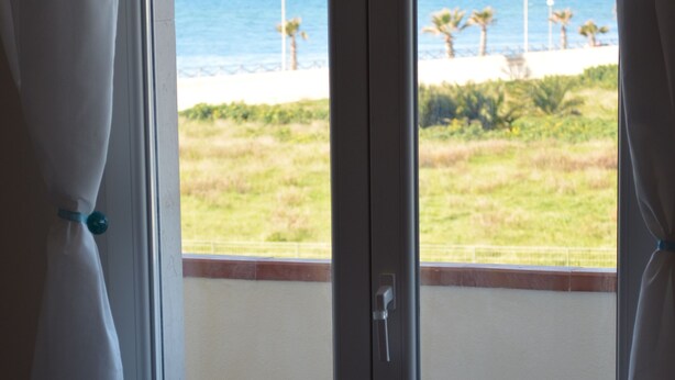 Una habitación con vista al océano a través de un ventanal corredizo.