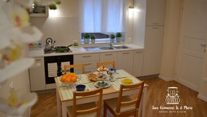 Una cocina con una mesa de comedor para cuatro personas, un fregadero y una ventana con plantas.