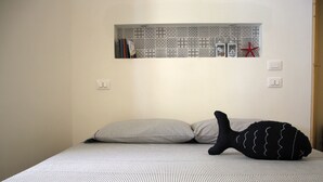 A bed with striped bedding, a pillow, and a black sock with a wavy pattern.