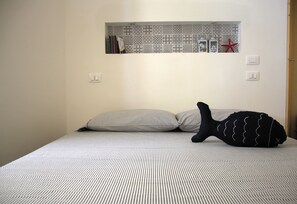 Un lit avec une literie à rayures, un oreiller et une chaussette noire à motifs ondulés.