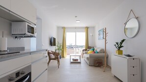 A modern kitchen with a microwave, oven, and a dining area with a table and chairs. There is a sofa and a small side table with a plant. - Great apartment in Playa de San Agustín. (San Agustin)