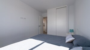 A bedroom with a bed, a nightstand, and a door leading to another room. - Great apartment in Playa de San Agustín. (San Agustin)