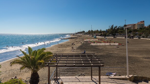 A beach with a wooden pergola, palm trees, and a clear blue sky. - Great apartment in Playa de San Agustín. (San Agustin)
