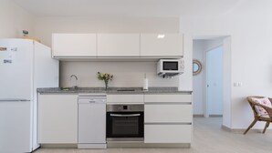 A modern kitchen with white cabinetry, a built-in dishwasher, an oven, and a microwave. - Great apartment in Playa de San Agustín. (San Agustin)