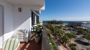 A balcony with a view of the sea, a parking area, and a building with a white facade. - Great apartment in Playa de San Agustín. (San Agustin)