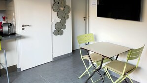 Eine kompakte Küche mit Essbereich, einem an der Wand befestigten Fernseher und einer Tür mit dekorativer, runder Platte.