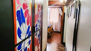 A hallway with a herringbone floor pattern and colorful floral wall panels.