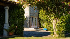 A stone building with a tiled roof, a stone column, and a paved entrance.