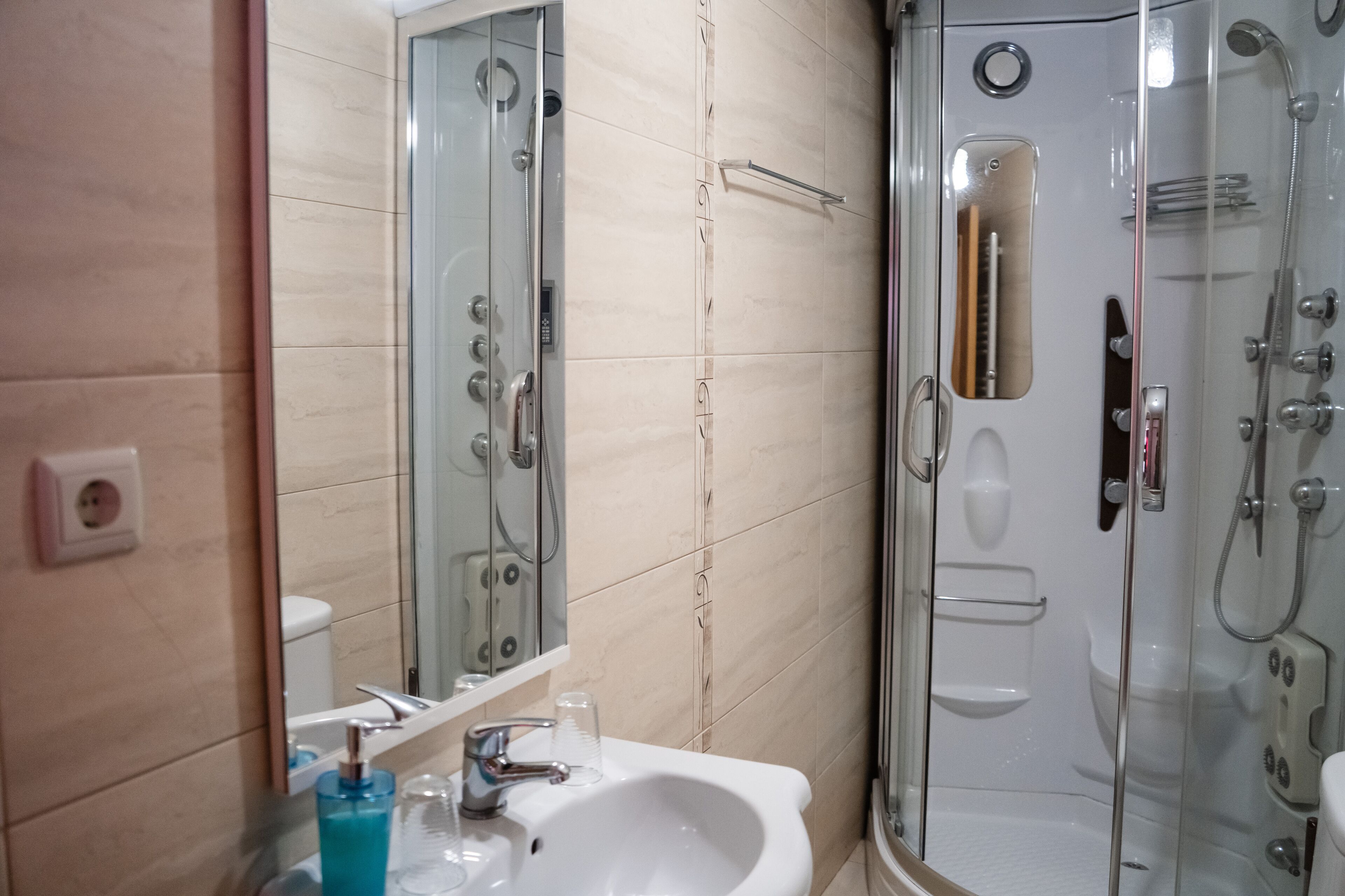 A bathroom with a glass-enclosed shower, a sink with a mirror, and a toilet.