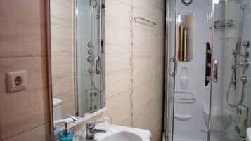 A bathroom with a glass-enclosed shower, a sink with a mirror, and a toilet.