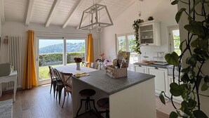 Une cuisine moderne dotée d’un îlot central, de planchers en bois et offrant une vue sur l’extérieur.