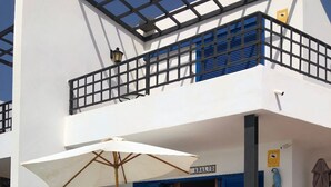 A pool area with a table and chairs, a covered umbrella, and a blue door.