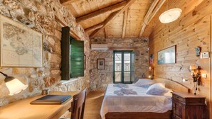 Une pièce rustique en bois, avec un mur en pierre, un lit, un bureau avec un ordinateur portable et une chaise.