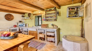 Une cuisine rustique avec des poutres en bois, un évier en pierre et une variété d’ustensiles de cuisine.