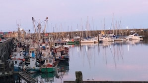 A marina with various boats docked, wooden walkways, and a calm water surface reflecting the boats.
