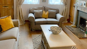A cozy living room with a sofa, a coffee table, and a fireplace.