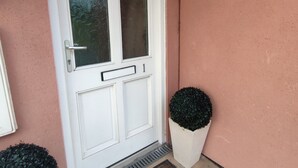 A white door with a glass panel, a small mailbox, and a doormat. - Pebbles Superb Apartment/Woodland & Sea View/Short Walk Beach/Free Parking &WiFi (Saundersfoot)