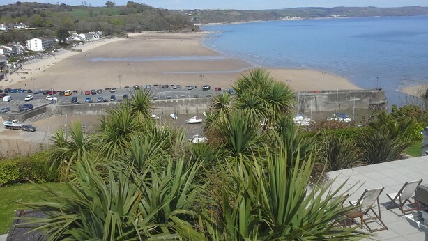 A coastal view with a beach, parking area, and buildings. - Pebbles Superb Apartment/Woodland & Sea View/Short Walk Beach/Free Parking &WiFi (Saundersfoot)