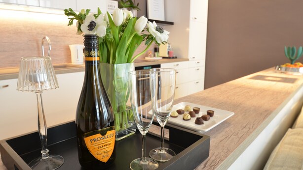 En bar med en Prosecco-flaske, to glas og en tallerken med chokolade.