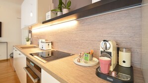 Et moderne køkken med træbordplade, kaffemaskine, brødrister og vask.