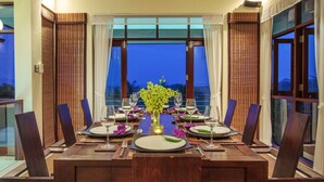 A dining area with a long table set for six, featuring a vase of flowers, wine glasses, and plates. - Villa Maphraaw - Self Isolation Promo (Mae nam)