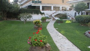 A landscaped garden with a stone pathway leading to a building with a staircase. - Dream holiday in Carihuela (Torremolinos)