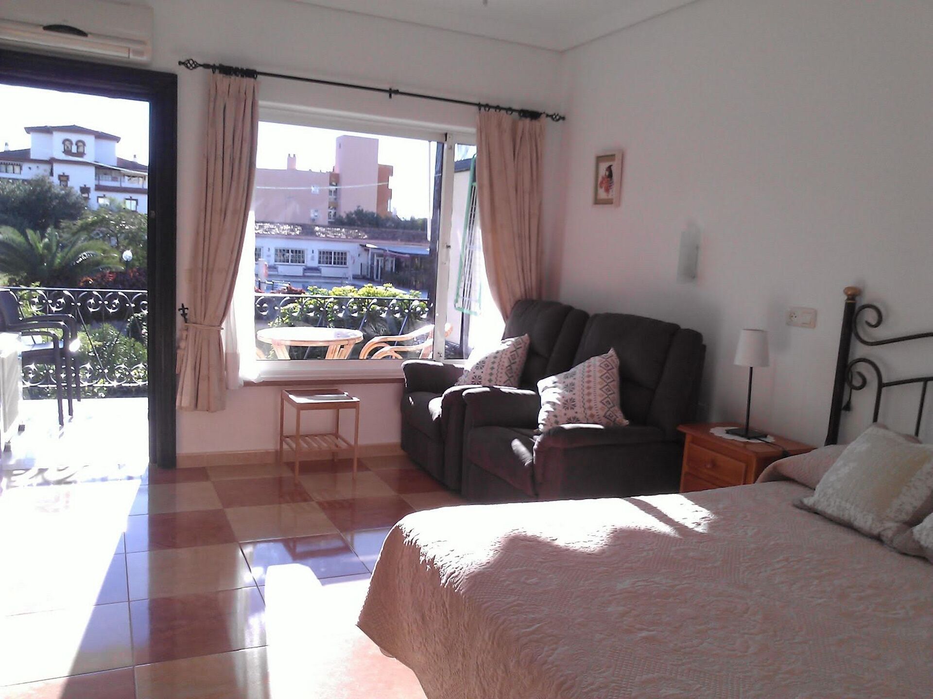 A bedroom with a bed, a sofa, a small table, and a window with curtains. - Dream holiday in Carihuela (Torremolinos)