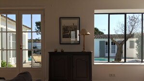 Een kamer met een donker houten kast, een ingelijst schilderij aan de muur, en een raam met uitzicht op een zwembad en een boom.