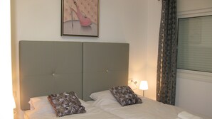 Een hotelkamer met een tweepersoonsbed, twee kussens, een hoofdbord, een bedlampje en een ingelijst schilderij aan de muur.