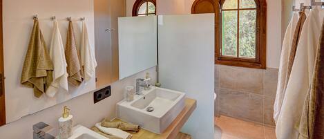 Een moderne badkamer met twee wastafels, een grote spiegel en een raam met een rondboogvormig ontwerp.