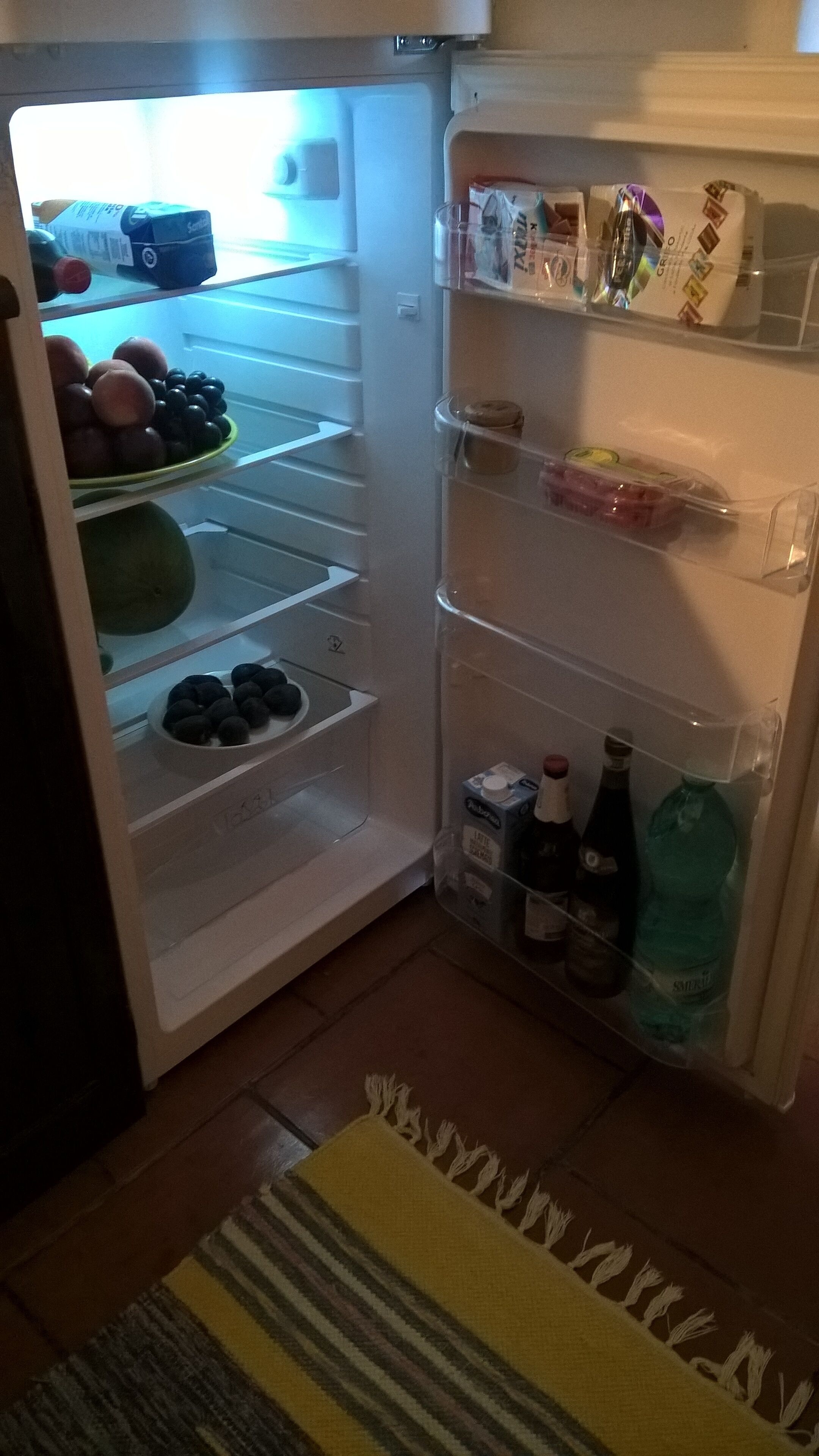 Auki oleva jääkaappi, jonka hyllyillä on erilaisia elintarvikkeita ja juomia.