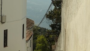 Un vicolo stretto con un edificio bianco, un cancello in metallo e un lampione.