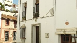 Un edificio bianco con tetto in tegole, una porta di legno e un piccolo balcone.