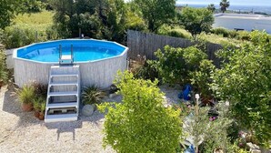 An outdoor swimming pool surrounded by greenery and a wooden fence. - Chill out and relax in true Portuguese style  (Santa Barbara de Nexe)