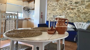 A rustic kitchen with stone walls, wooden beams, and a round table with woven placemats. - Chill out and relax in true Portuguese style  (Santa Barbara de Nexe)