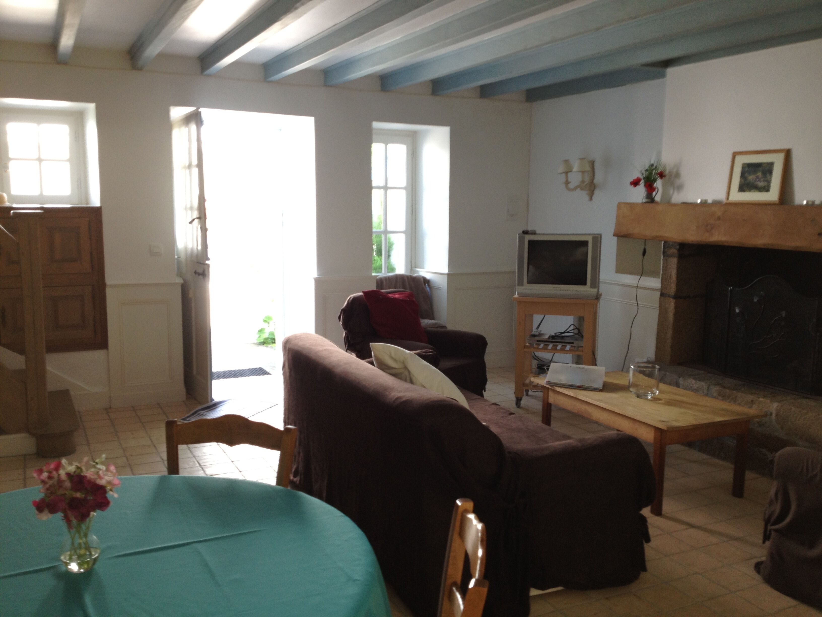 A living room with a fireplace, a television, and a dining area with a table set for two.